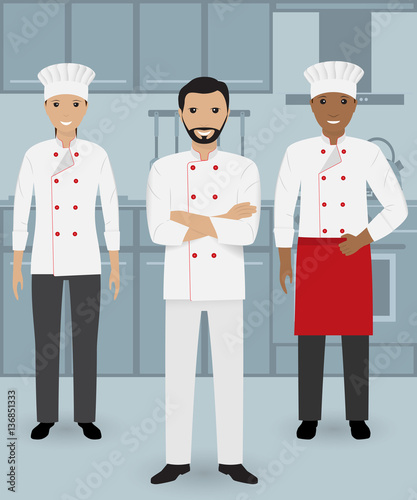 Chef and two cook in uniform standing together in three different poses on a kitchen background.