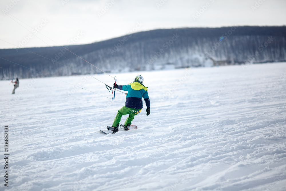 Men ski kiting on a frozen lake