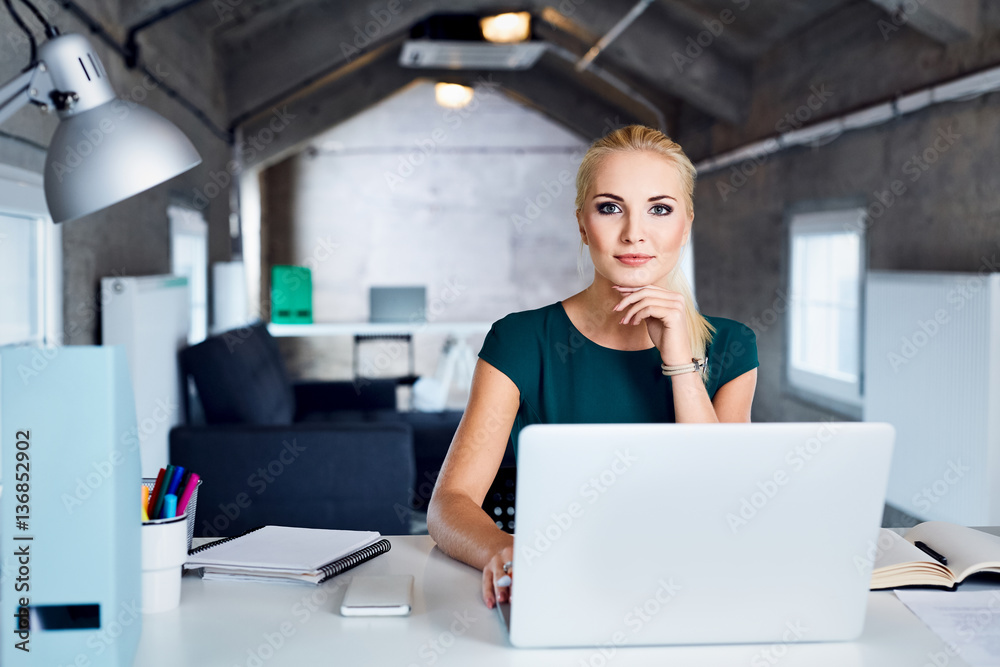 Beautiful young woman sitting at table in modern coworking office Beautiful young woman sitting at table in modern coworking office