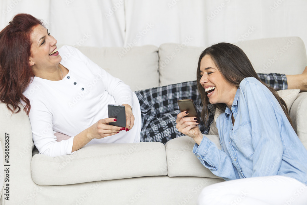 Two happy young female friends having fun together using smartphone Two happy young female friends having fun together using smartphone
