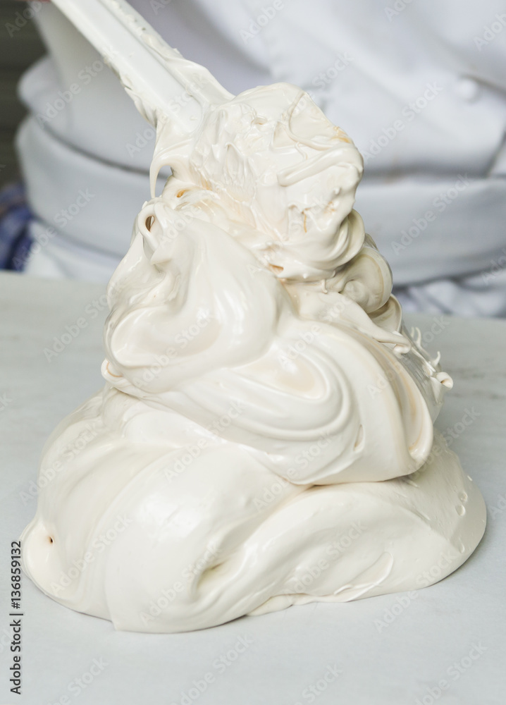 A beautiful rich and creamy , white whipped meringue mixture being scooped out onto a kitchen surface.