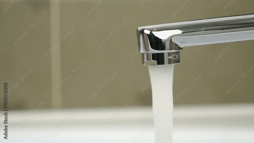 Chrome-plated faucet. Stream of water pouring from chrome-plated faucet. Close-up Chrome-plated faucet. Stream of water pouring from chrome-plated faucet. Close-up