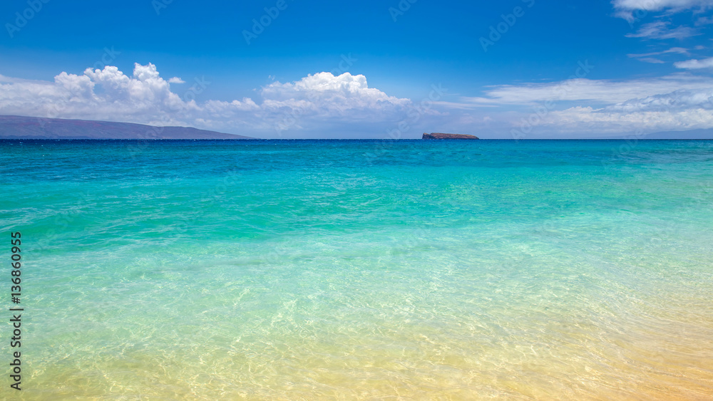 blue water at Makena Beach, Maui, Hawaii with Molokini crater at the horizon. Molokini is a crescent shaped island, the tip of an underwater volcano and a Snorkelling and diving destination 