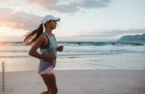 Fit young woman jogging at the beach in morning