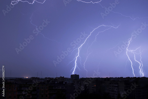 Lightning in the night sky strikes the roof of the house