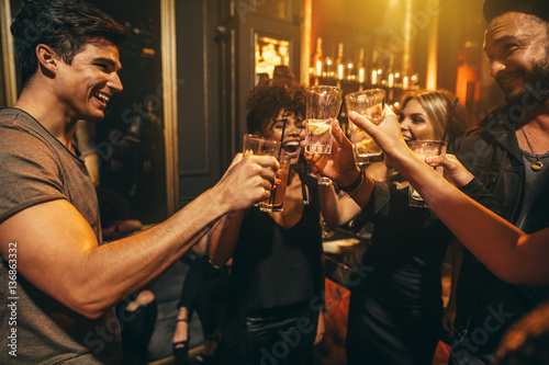 Fotografie, Obraz Group of men and women enjoying drinks at nightclub