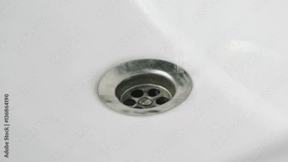 Draining the water into the white sink. Close-up Draining the water into the white sink. Close-up