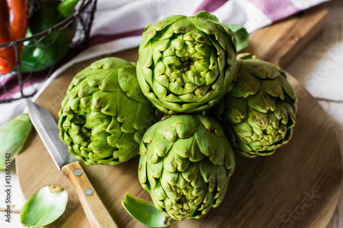 Fresh green artichokes on cutting board with peeled off leaves, photo