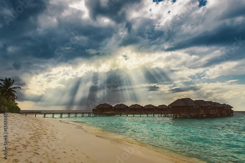 Heaven sun rays over water bungalows at tropical island resort photo