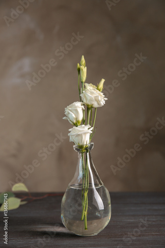 Glass vase with bouquet of beautiful flowers on color background