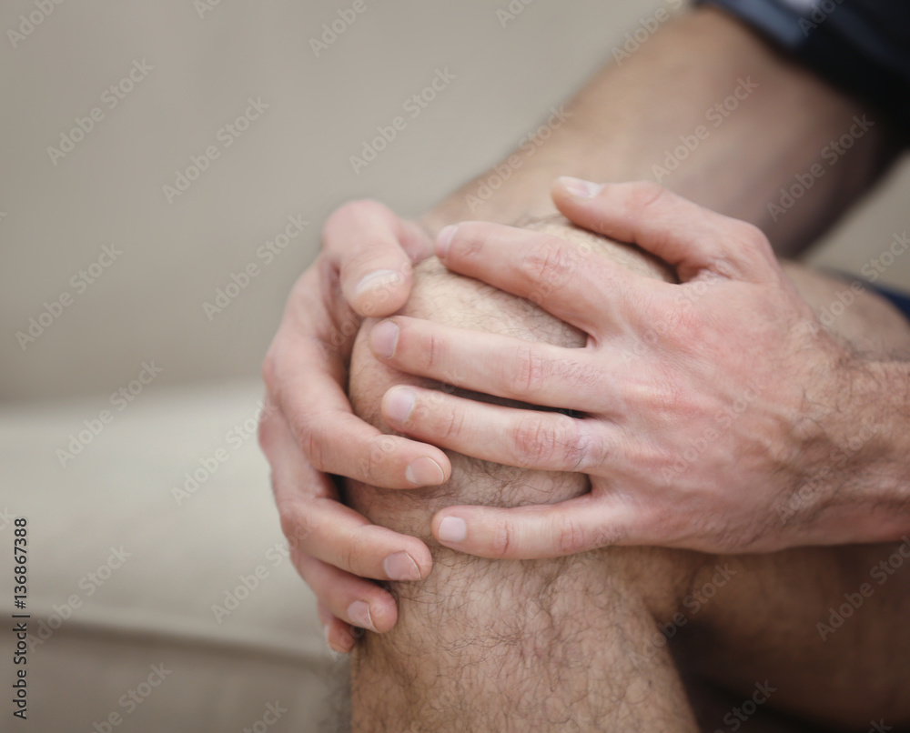 Fototapeta premium Man suffering from knee pain at home, closeup