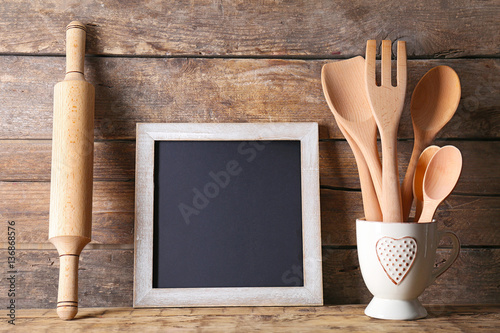 Kitchen utensils and blank blackboard on wooden background