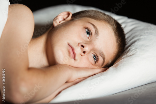 Young boy with open eyes and head on pillow