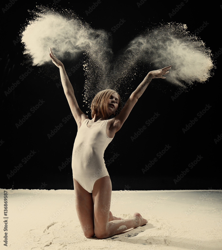 Naklejka premium Little cute girl dancing with white powder on black background