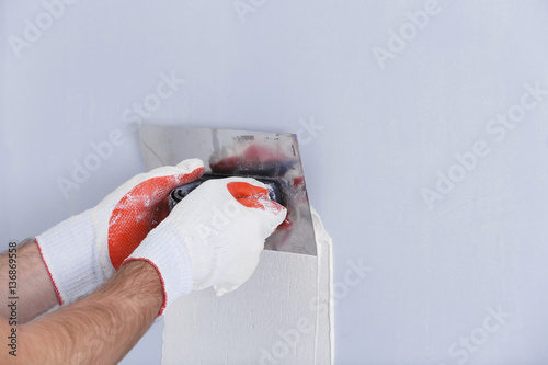 Builder using plastering tool for finishing wall photo