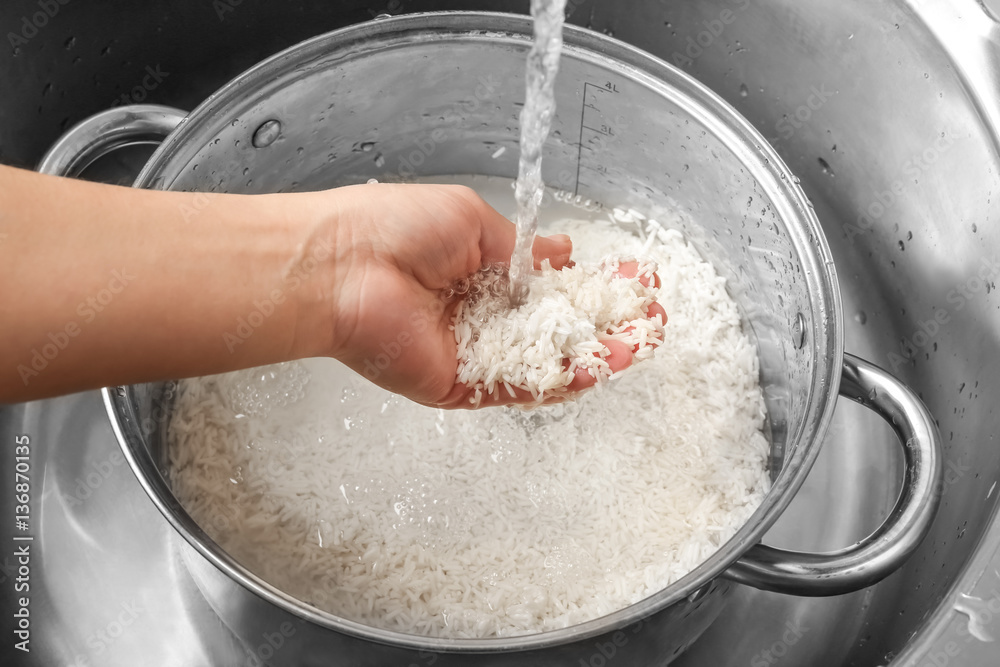 Fototapeta premium Woman rinsing rice in saucepan