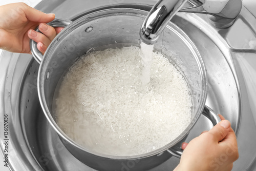 Woman rinsing rice in saucepan