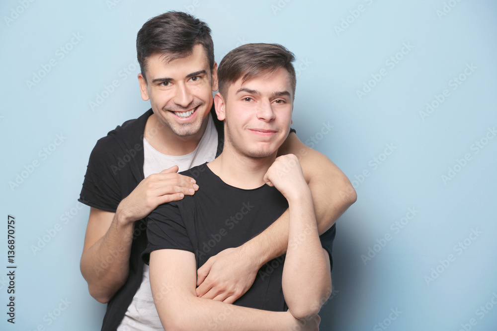 Happy gay couple posing on light background Happy gay couple posing on light background
