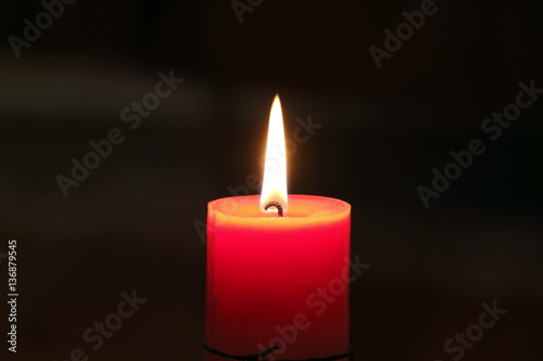 Burning candle on a dark blured background