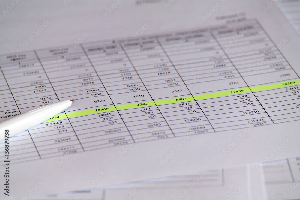 Pen layin on printed financial report in the form of table with numbers Pen layin on printed financial report in the form of table with numbers