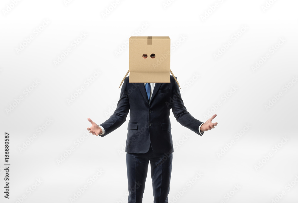 Businessman is staying his hands to the sides with a box on his head with holes for eyes on white background Businessman is staying his hands to the sides with a box on his head with holes for eyes on white background