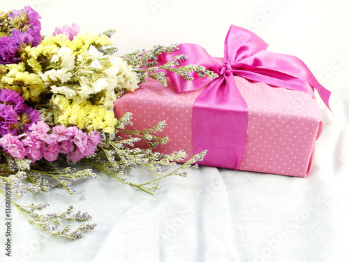 craft paper gift box with ribbon bow and flower bouquet with fabric texture