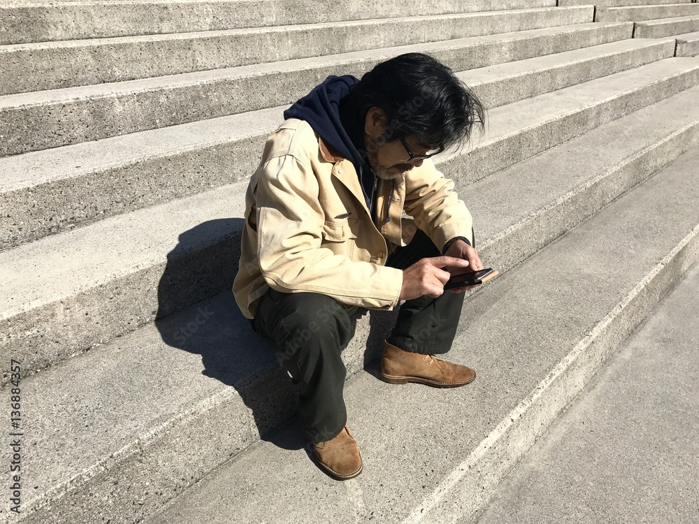 階段に座り携帯電話を操作する男性 階段に座り携帯電話を操作する男性