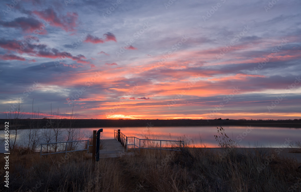 Fototapeta premium Colorful sunrise reflection on a lake with a fishing dock