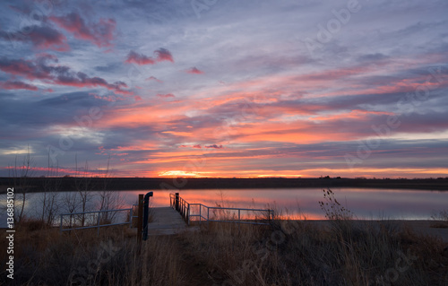 Colorful sunrise reflection on a lake with a fishing dock