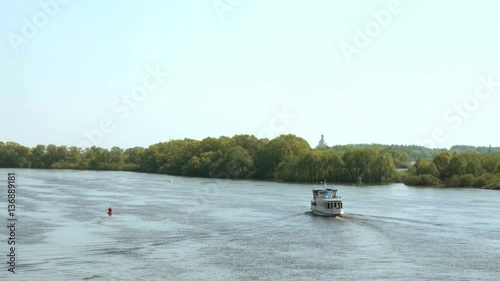 White ship with tourists floating along Volkhov river in the direction Yuriev Monastery in Velikiy Novgorod, Russia. Summer, beautiful weather photo