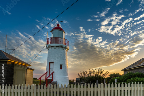 Lighthouse at Sunset. Romantic historic lighthouse in Warrnambool Australia, taken during sunset. Wooden fence in the foreground. Colorful sky.