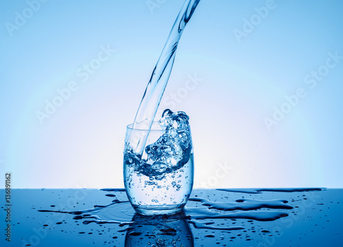 Obraz na plátně Bottle with creative splashing water in the glass