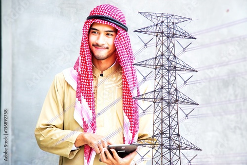 Arabian man is holding tablet with pylon background.