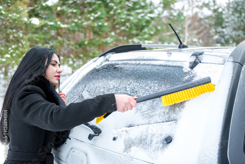 Woman cleaning car windshield of snow winter happy young scraper