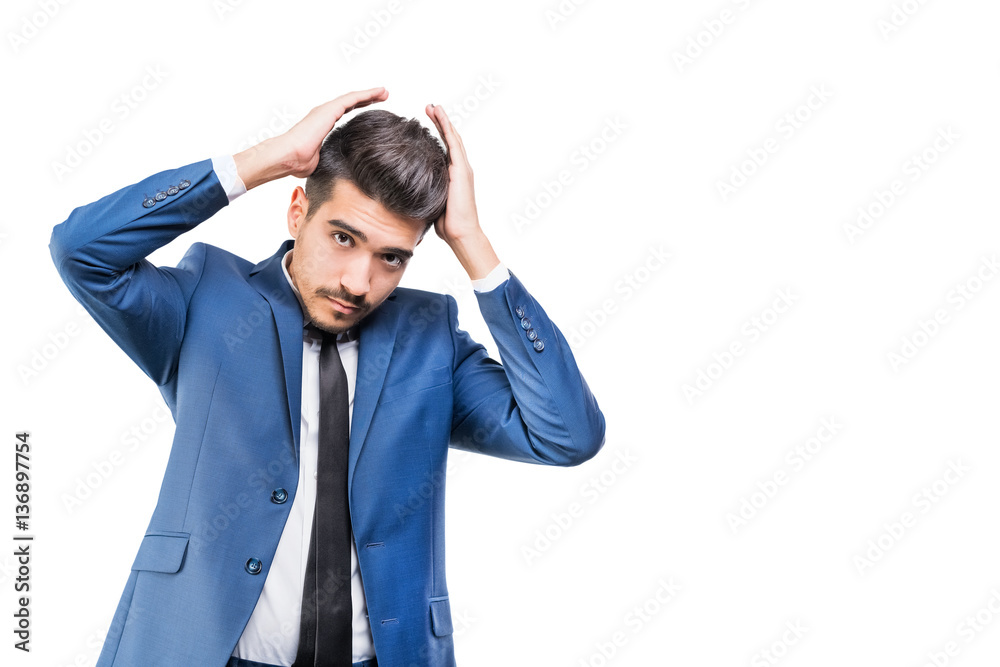 Young attractive man in a blue suit with hands near the head on a white background. Isolated Young attractive man in a blue suit with hands near the head on a white background. Isolated