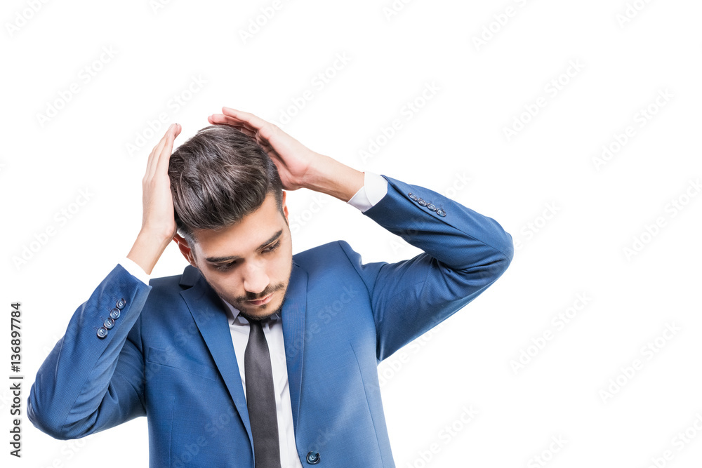 Young attractive man in a blue suit with hands near the head on a white background. Isolated Young attractive man in a blue suit with hands near the head on a white background. Isolated