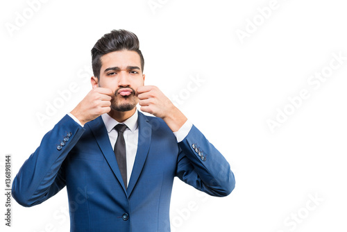 Young attractive man in a blue suit touches his hands cheeks on a white background. Isolated