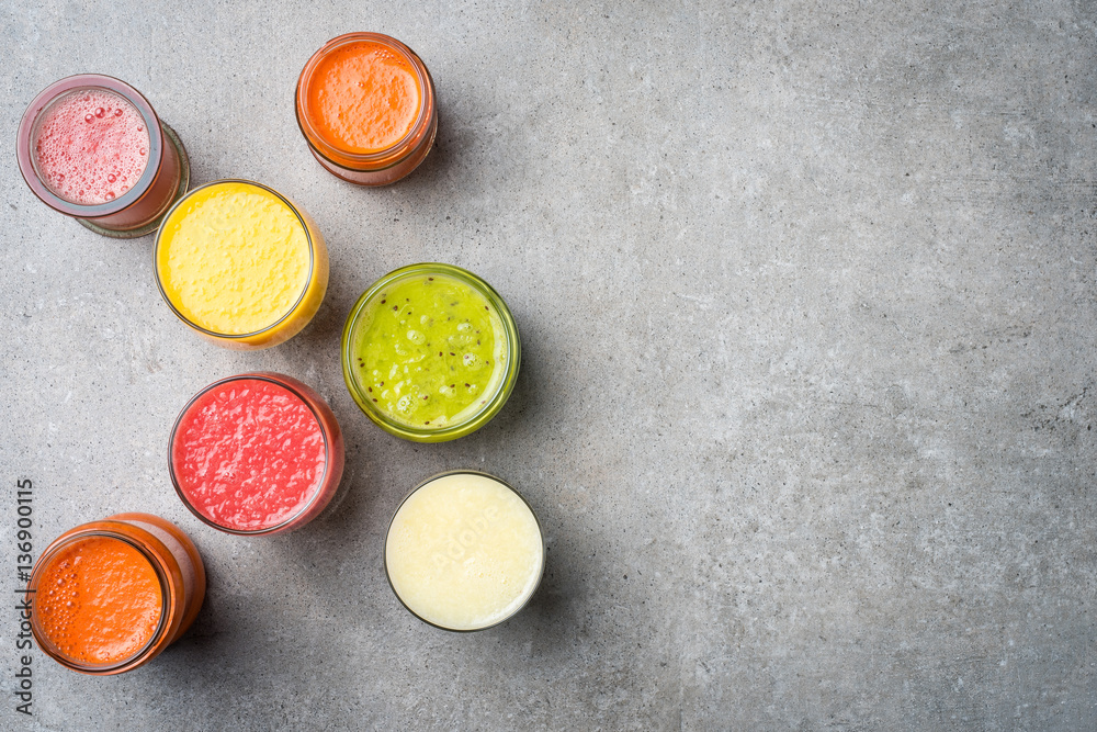 Glasses of fresh juice on gray stone table. Food background Glasses of fresh juice on gray stone table. Food background