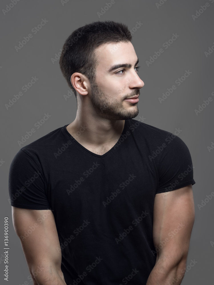 Profile view of happy confident young fit man in blank black shirt looking away over gray studio background. Profile view of happy confident young fit man in blank black shirt looking away over gray studio background.