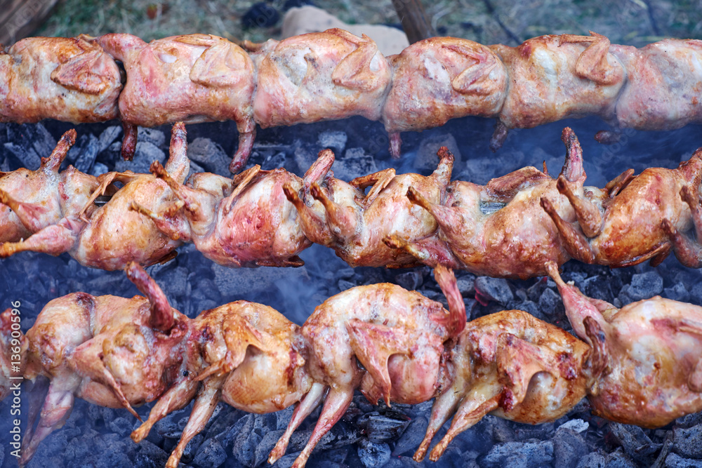 Chicken grilled on skewers over coals