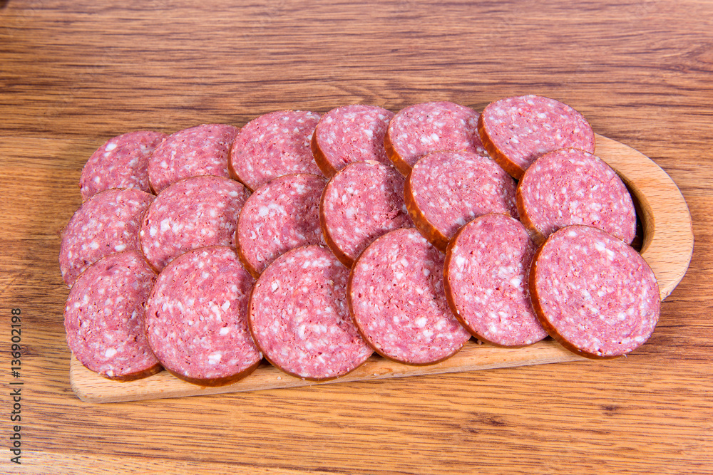 Close-up of chopped smoked sausage on a wooden board. Close-up of chopped smoked sausage on a wooden board.