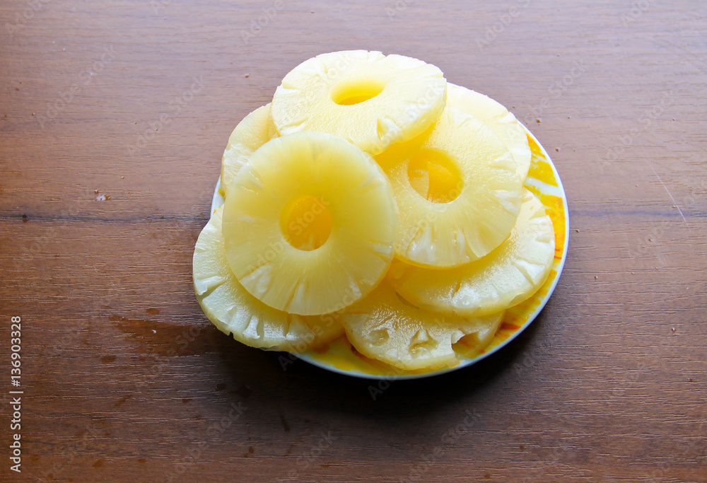 Canned pineapple on a plate on wooden table Canned pineapple on a plate on wooden table