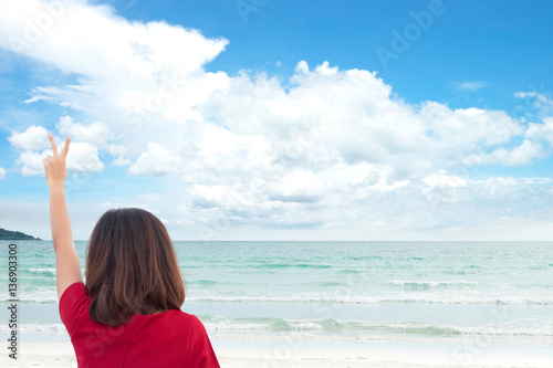 business woman ware red dress with bright sky, cloud on the beach and beautiful sea and sand. on holiday vacation festival. for travel background.