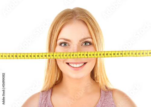 Young woman with measuring tape on white background