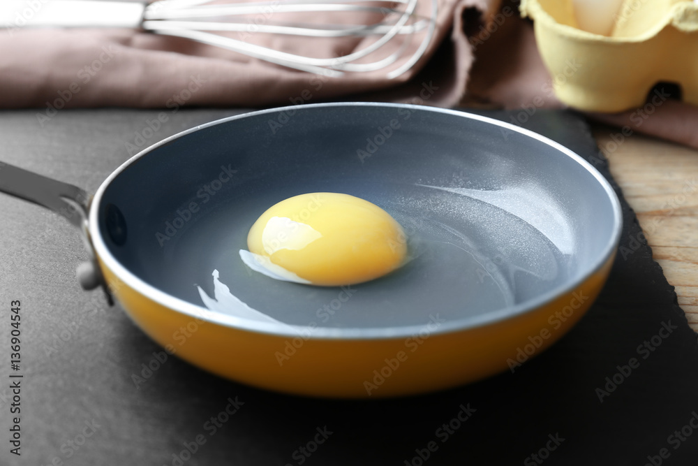 Fresh raw egg in frying pan on slate plate Fresh raw egg in frying pan on slate plate