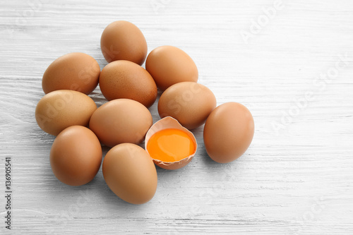 Raw eggs with yolk on wooden background