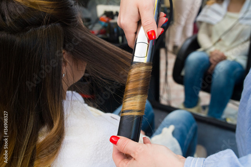 Professional hairdresser curling ombre hair with iron