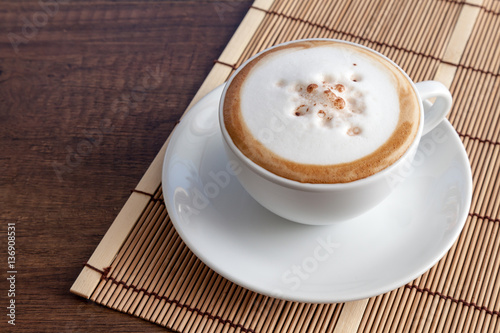 Obraz na płótnie Coffee cup of cappuccino on bamboo mat, on wooden background wit w salonie