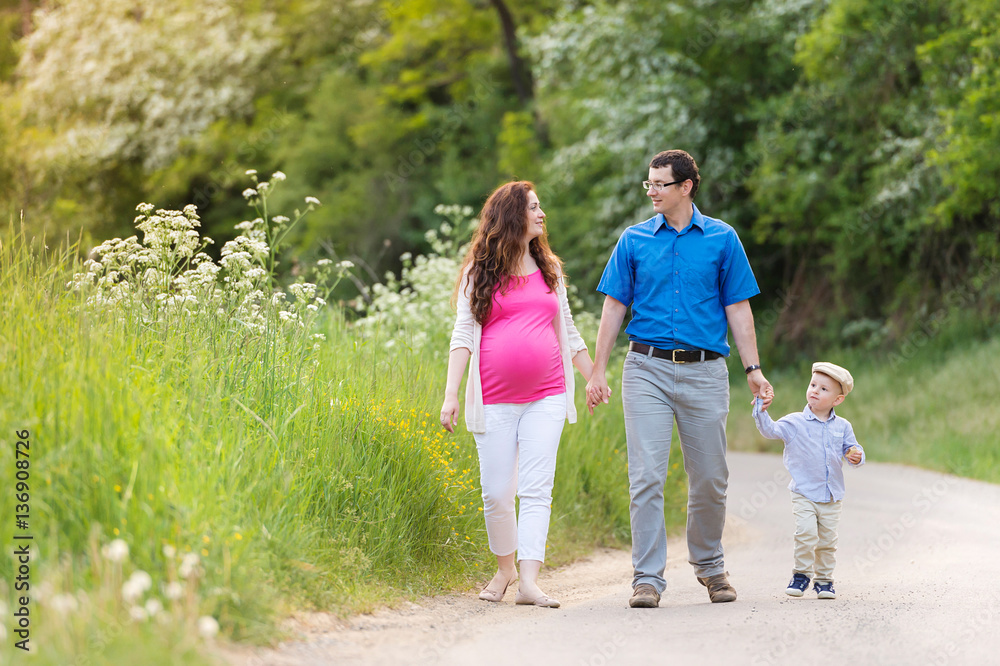 Young family walking on country road in green nature