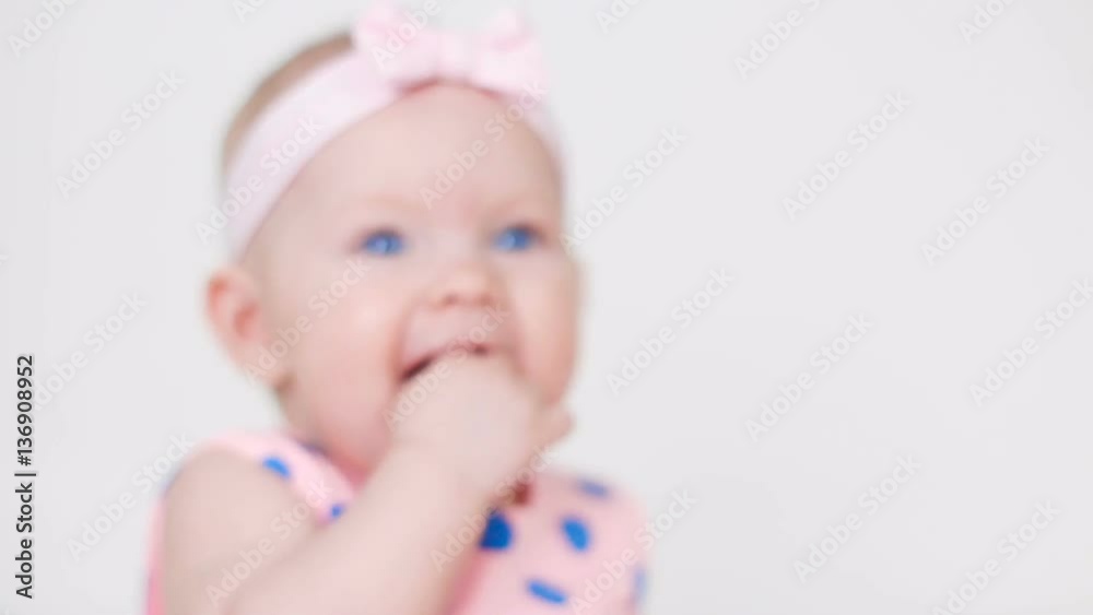 little girl in a pink polka dot dress with bandage on head sitting in the studio on a wooden floor